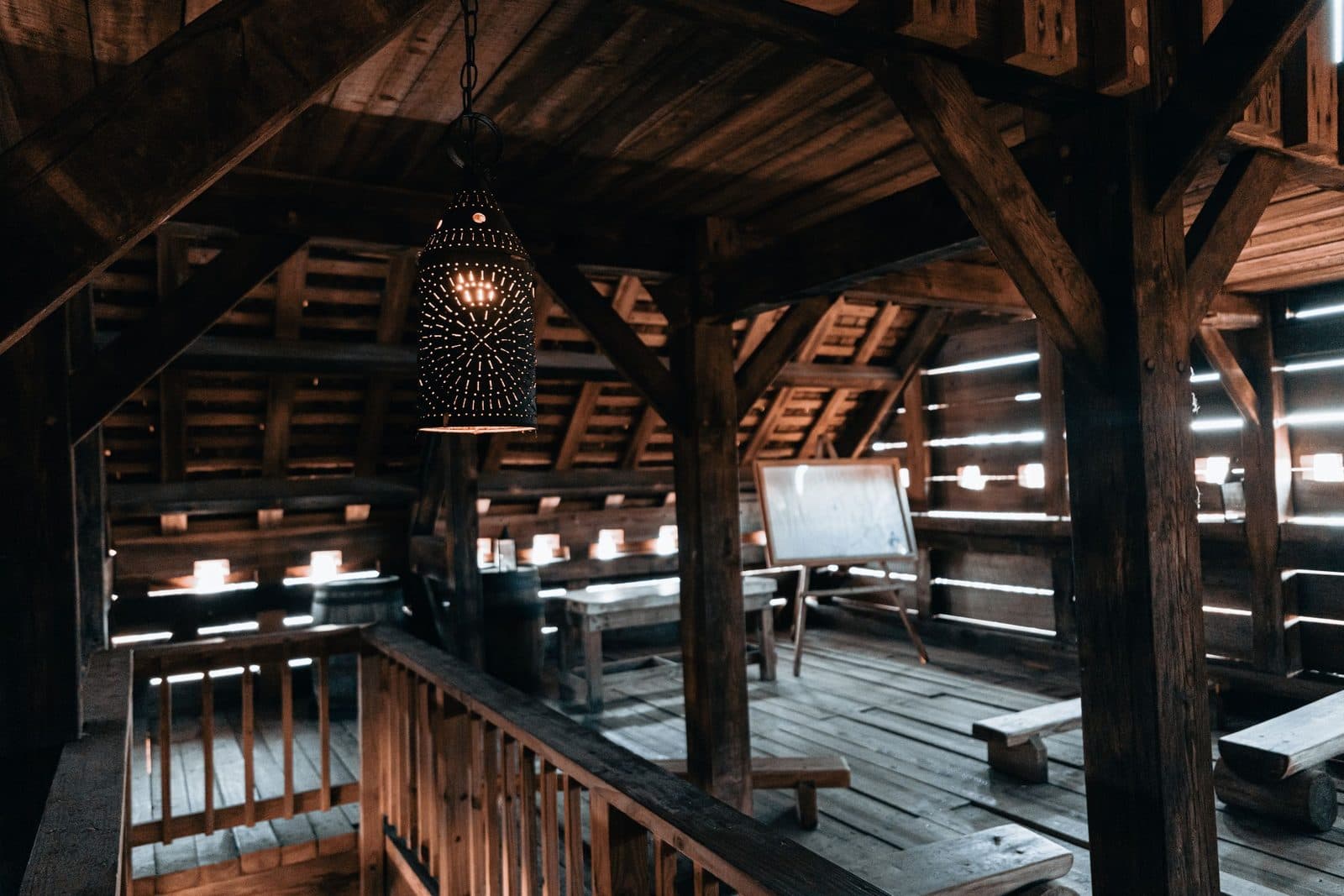 Grenier sous une charpente en bois ancienne, avec des meubles et des objets entreposés avant un débarras